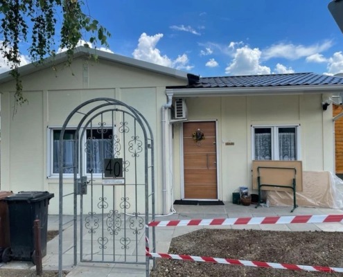 ein kleines Haus mit einen kleinen Garten davor und ein Stahltor